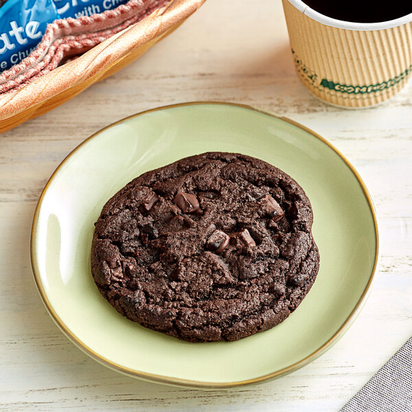 A Best Maid double dark chocolate chunk cookie on a plate next to a cup of coffee.