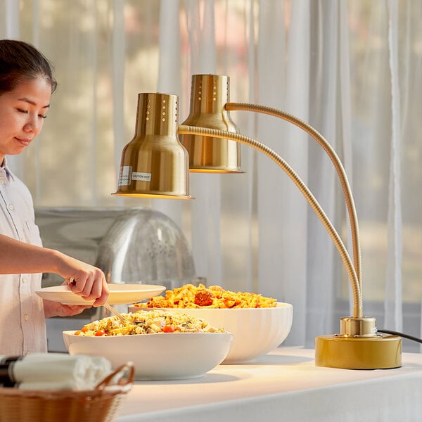 An Avantco gold dual arm flexible heat lamp over food on a white table.