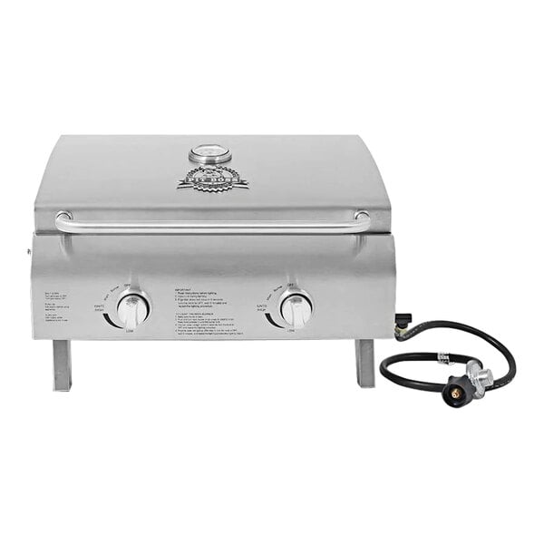A Pit Boss stainless steel table top gas grill with a hose attached.