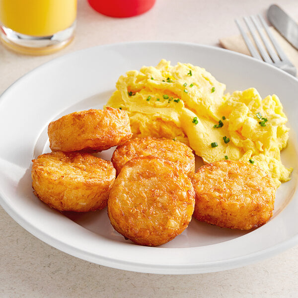 A plate of breakfast food with McCain Hash Brown Rounds, eggs, and a fork and knife.