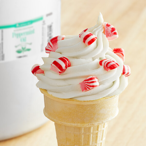 A close-up of a white and red ice cream cone with LorAnn Oils peppermint candy on top.