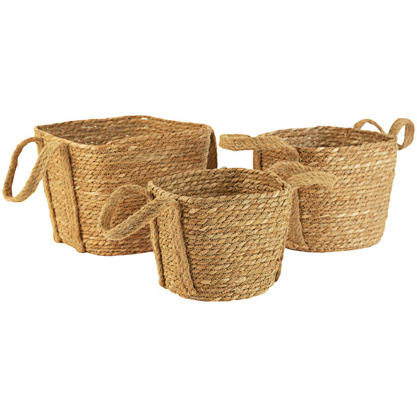 A group of three woven seagrass baskets with handles.
