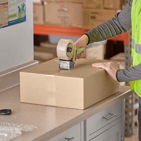 A person using a tape gun to seal a Lavex shipping box.