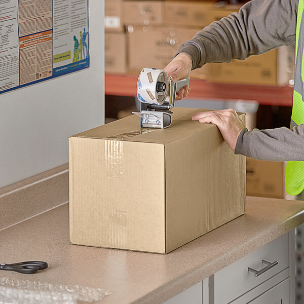 A person using a box cutter to cut a Lavex shipping box.