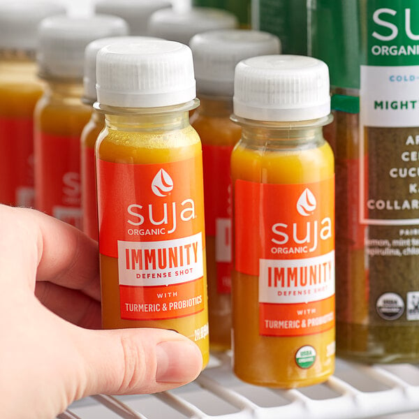 A person holding a bottle of Suja Immunity Defense Wellness juice.