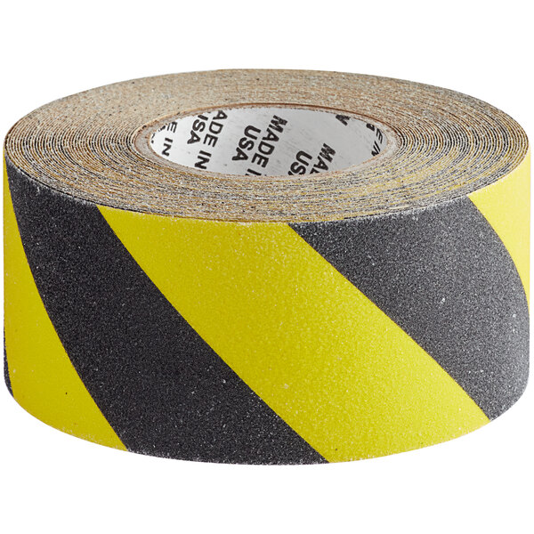 A roll of yellow and black tape with black grit surface and warning stripes.