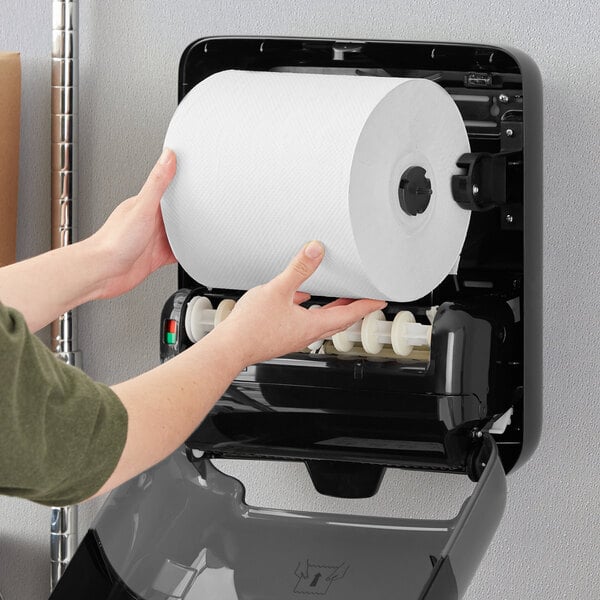 A person's hands holding a roll of Tork white paper towels.