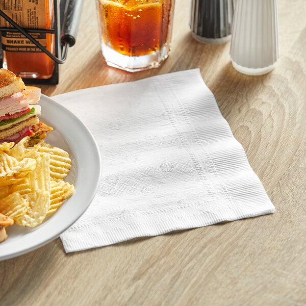 A plate of food and a Tork Universal white napkin on a table.