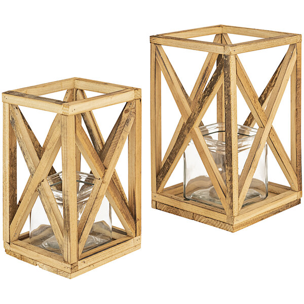 A pair of wooden lanterns with glass jars inside on a wooden stand.