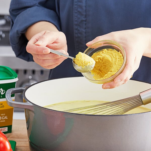 A woman stirring Knorr Professional Select Chicken Base into a pot of food.