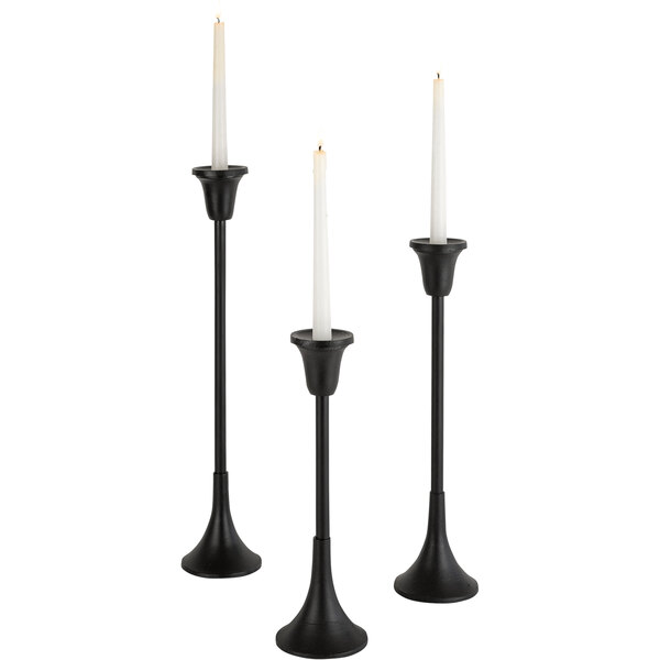 A group of black Kalalou cast iron candle holders with white candles on top.