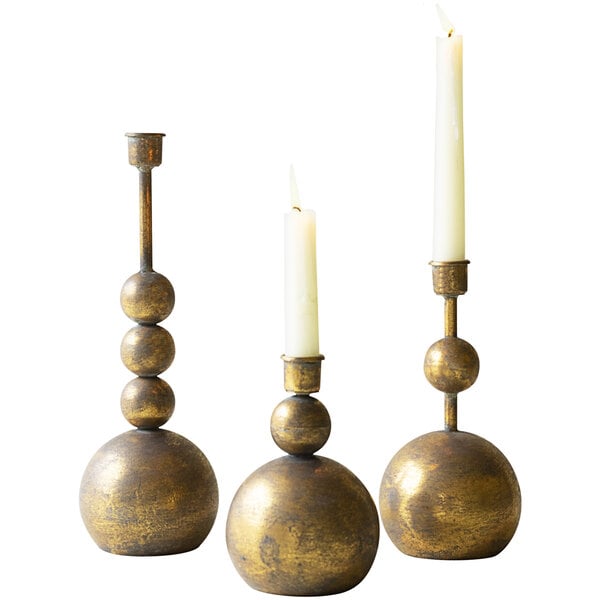 A group of Kalalou antique brass candlestick holders with lit candles.