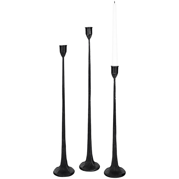 A group of black Kalalou cast iron candle holders with white candles.