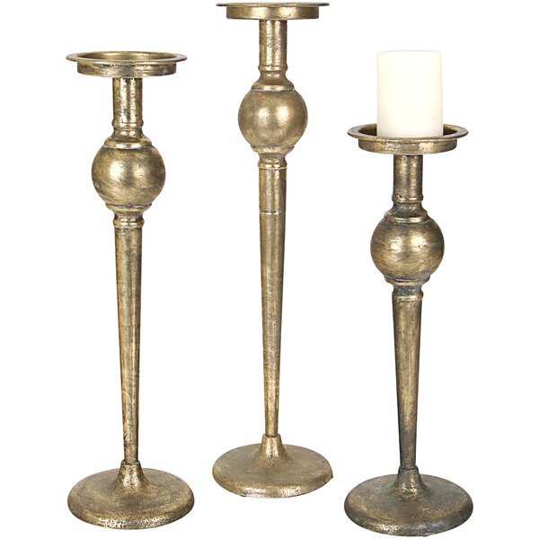 A group of Kalalou metal pillar candle holders with a lit white candle in each.