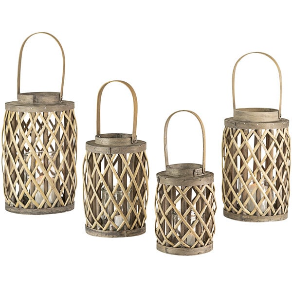 A group of three wooden lanterns with glass in a gray willow basket with a handle.