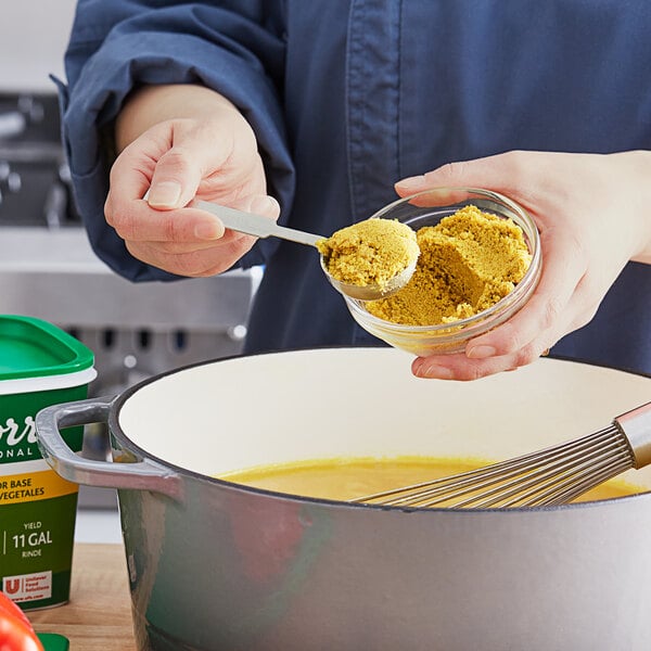 A person stirring Knorr Professional Select Vegetable Base into a pot of food.