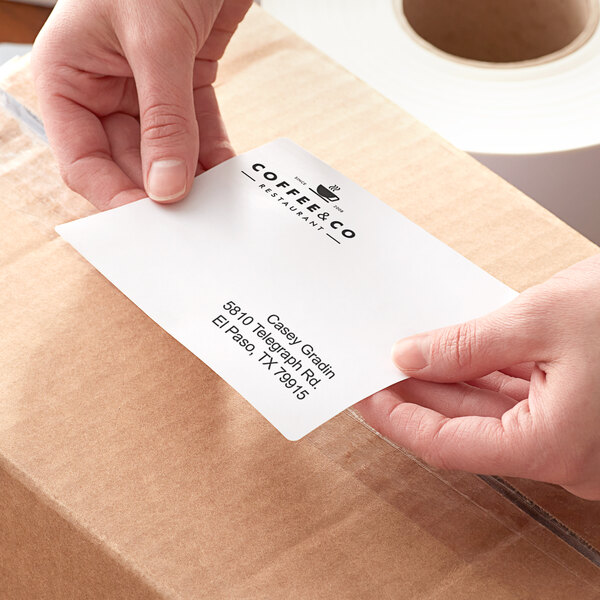A person using a Lavex white thermal transfer label on a box.