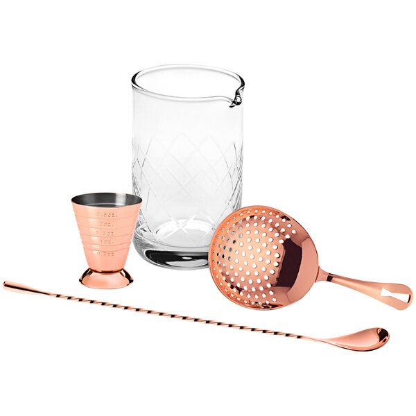 A copper cocktail shaker, strainer, and utensils in a glass.
