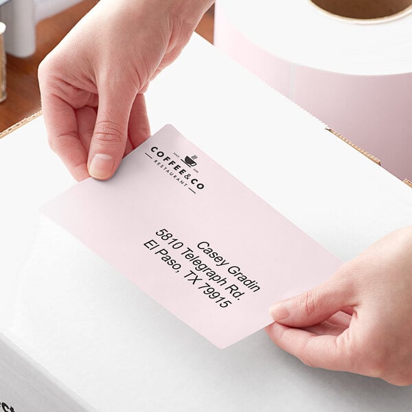 A person holding a pink piece of paper with a Lavex pink mailing label on it.