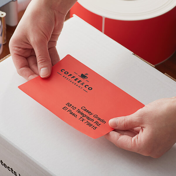 A hand placing a red Lavex thermal label on an envelope.