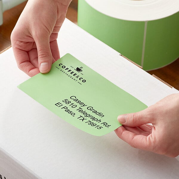 A person holding a green paper label on a box.