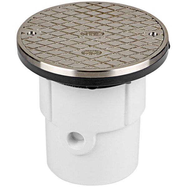 A white plastic PVC cleanout with a silver round strainer cover.