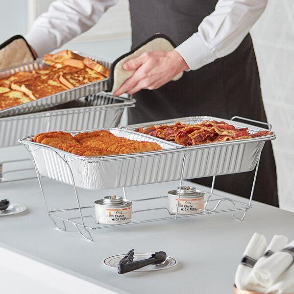 A man using a Choice disposable chafer dish kit to prepare food on a table for a catering event.