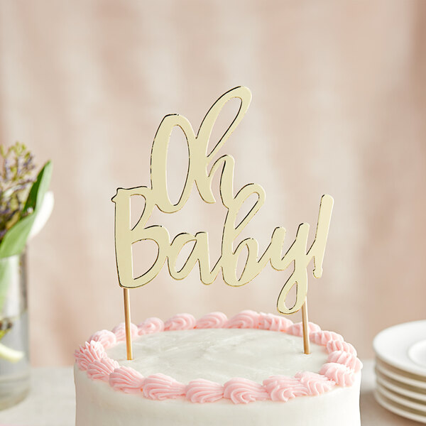 A close up of a cake with pink frosting and a gold "Oh Baby!" cake topper.