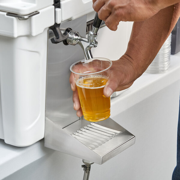 A person pouring a beer from a Regency stainless steel underbar mount jockey box beer drip tray.