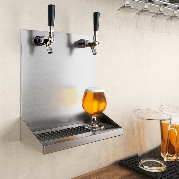 A Regency stainless steel beer drip tray with two faucets over a metal shelf with a glass of beer.