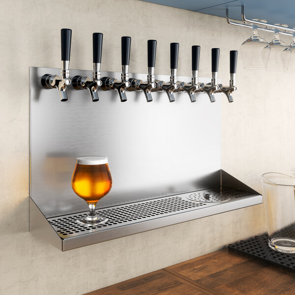 A Regency stainless steel wall mount drip tray with a glass of beer on a metal shelf.