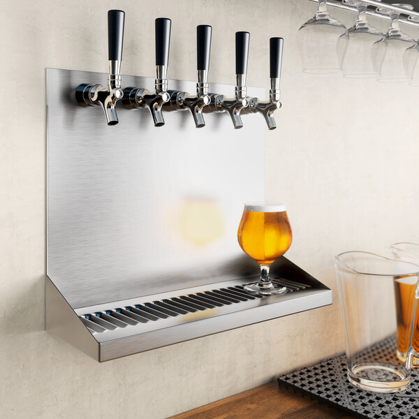 A Regency stainless steel beer drip tray with beer faucets and glasses of beer on a metal shelf.
