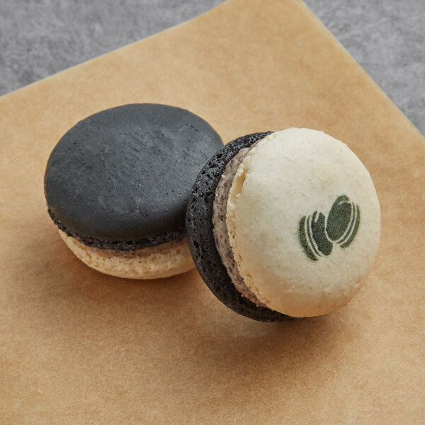 Two Macaron Centrale Cookies and Cream macarons on a table.