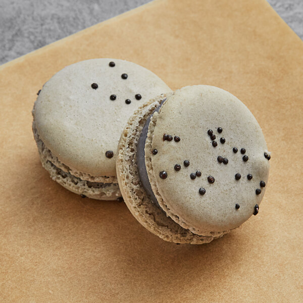Two Macaron Centrale macarons with black sprinkles on top.