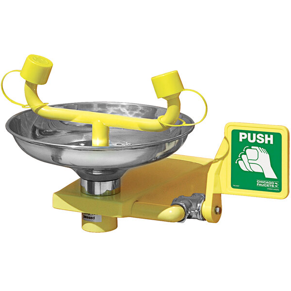 A yellow push button station for a Chicago Faucets wall-mounted eye wash faucet.
