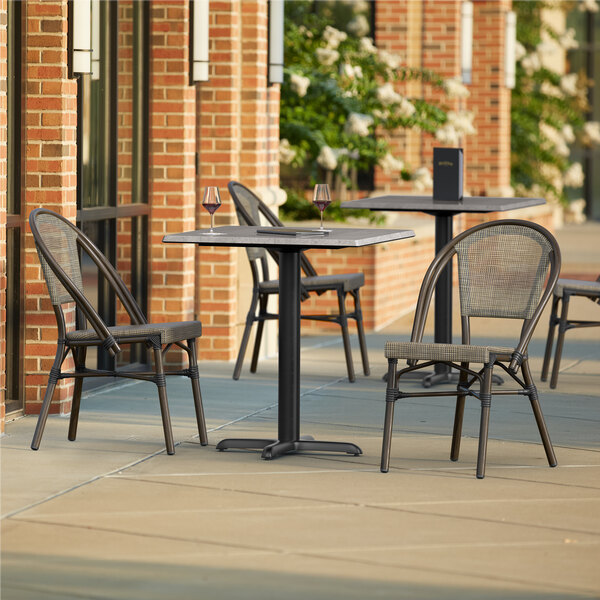 A Lancaster Table & Seating Excalibur square table with two chairs on an outdoor patio.