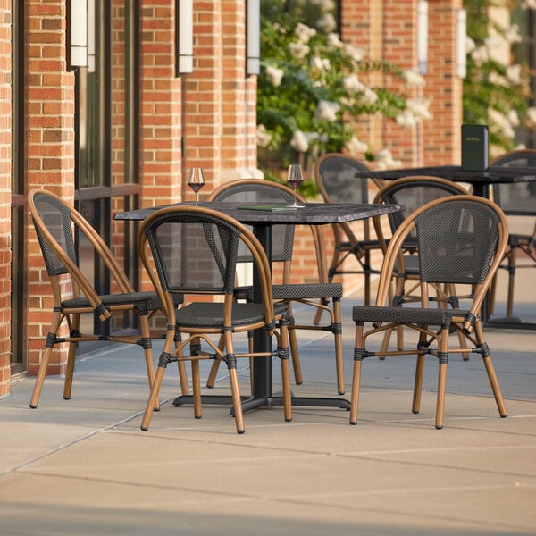 A Lancaster Table and Seating Paladina table with black chairs on a patio.