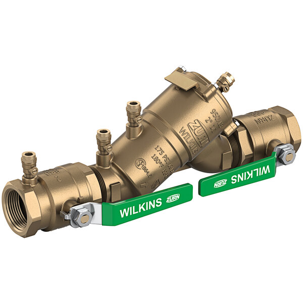 Two Zurn brass backflow preventers with green labels on a gold metal pipe.