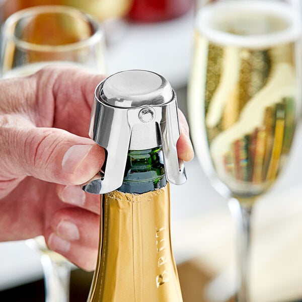 A hand using the Choice stainless steel champagne stopper to open a champagne bottle.