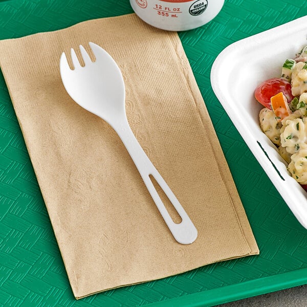A white World Centric compostable spork on a napkin next to a bowl of food.