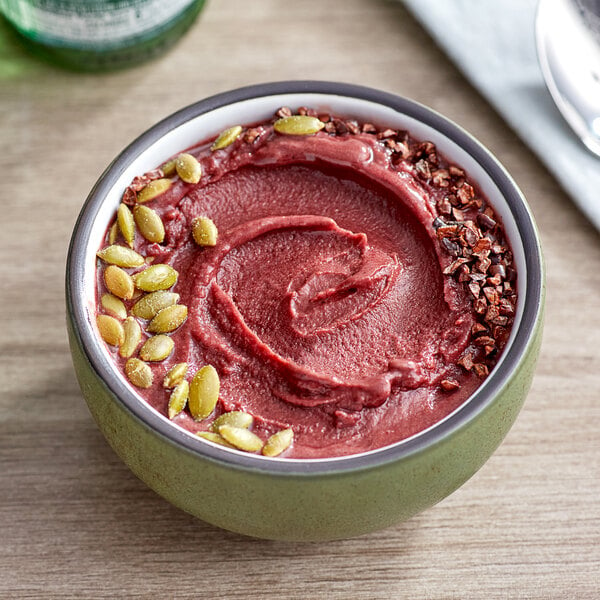 A bowl of red Sambazon Acai smoothie with seeds.
