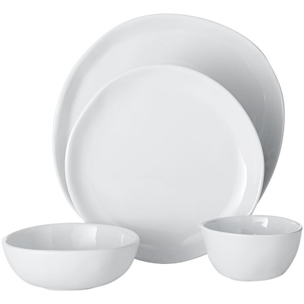 A stack of white plates and bowls with a white place setting.