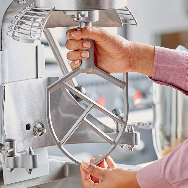 A person attaching an Avantco flat beater to a mixer.