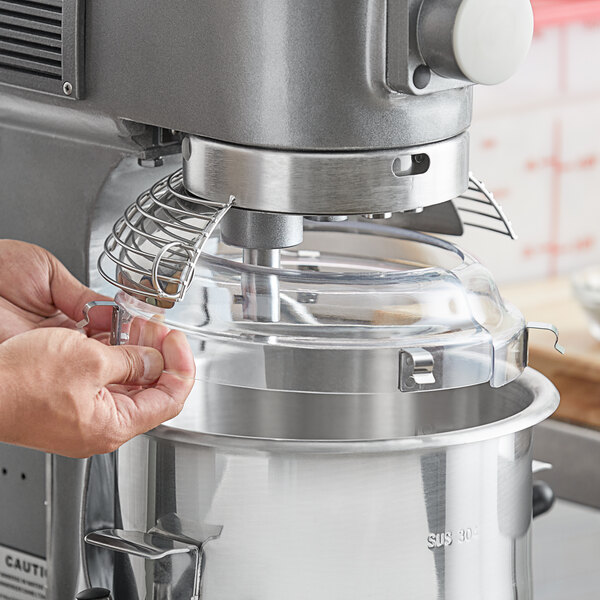 A person using an Avantco mixer with a splash cover.