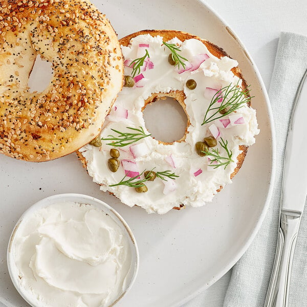 A bagel with GOOD PLANeT cream cheese and onions on a plate.