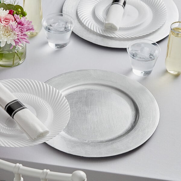 A white table setting with silver Choice charger plates on a white table.