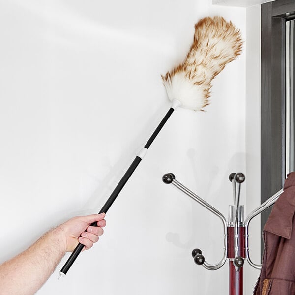 A hand holding a Lavex lambswool duster with a telescopic handle.