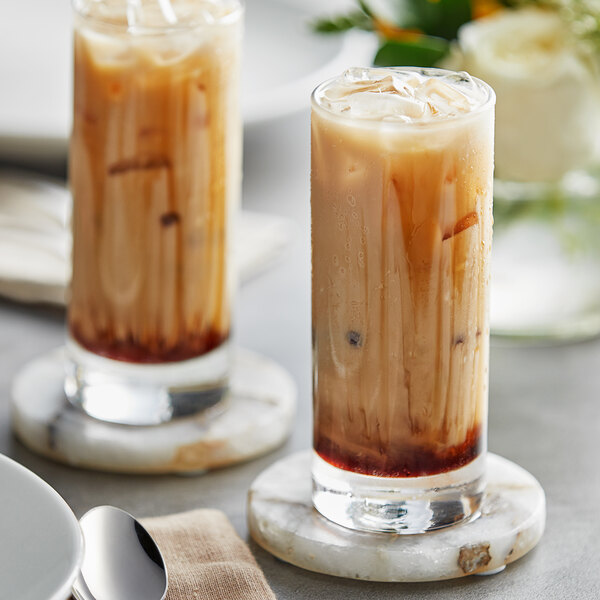 Two glasses of Fanale Brown Sugar syrup iced coffee on a table with coasters.