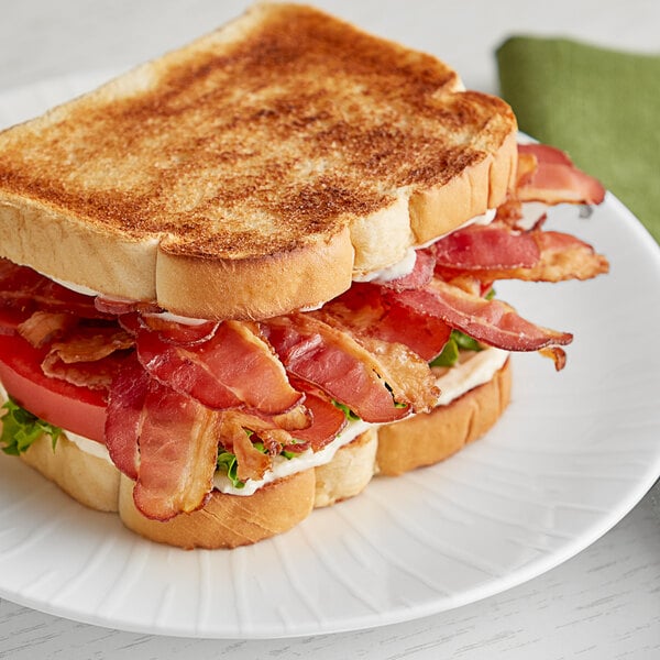 A sandwich on a plate with Swift Fully Cooked Thin Bacon, lettuce, and tomatoes.