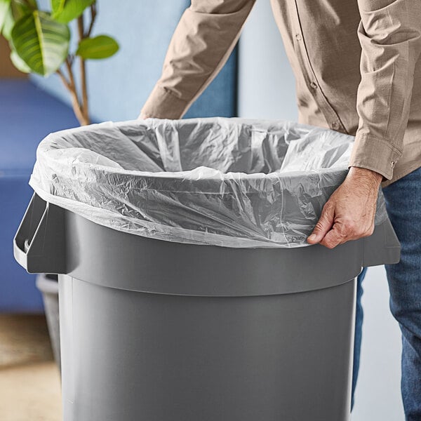 A man using a Lavex high density trash bag in a grey trash can.